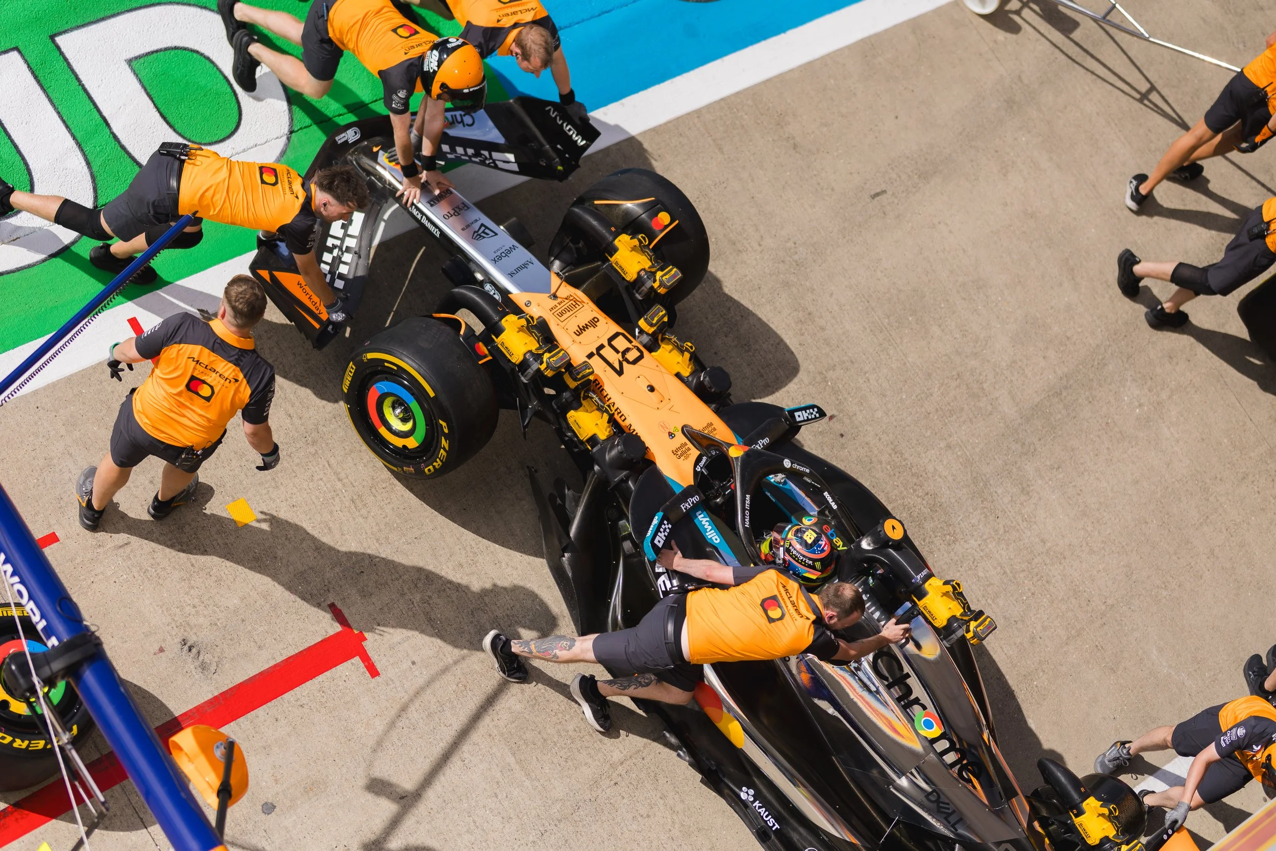 Race car in the pit lane being serviced by a team of mechanics and engineers.