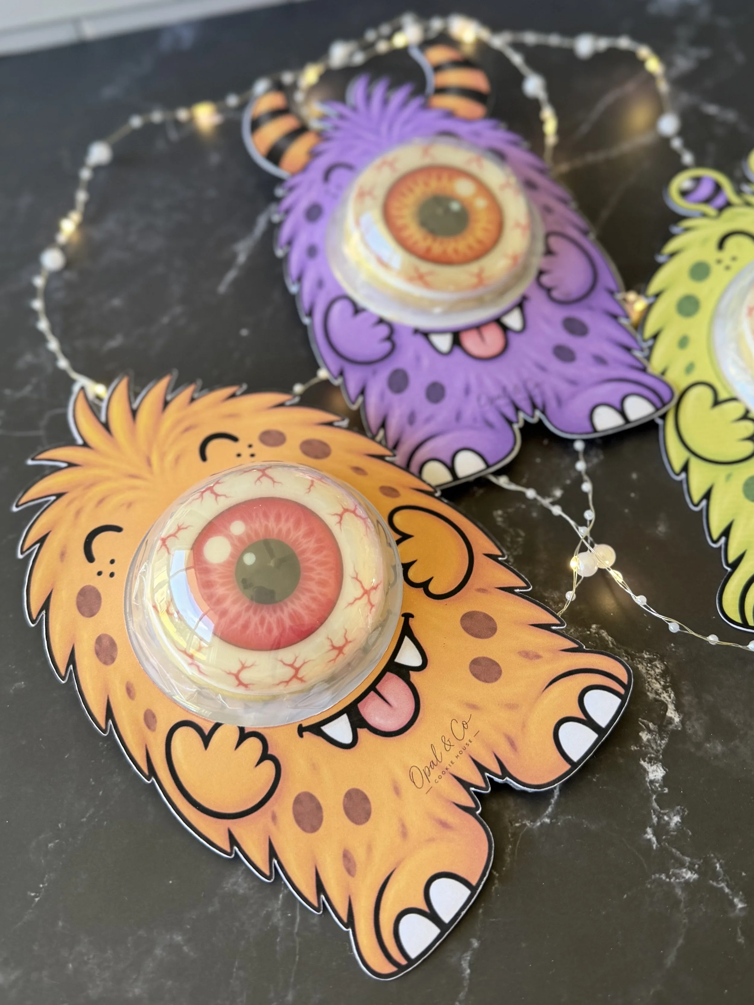 Colourful Halloween monster sugar cookies with edible printed designs and 3D eyeball decorations