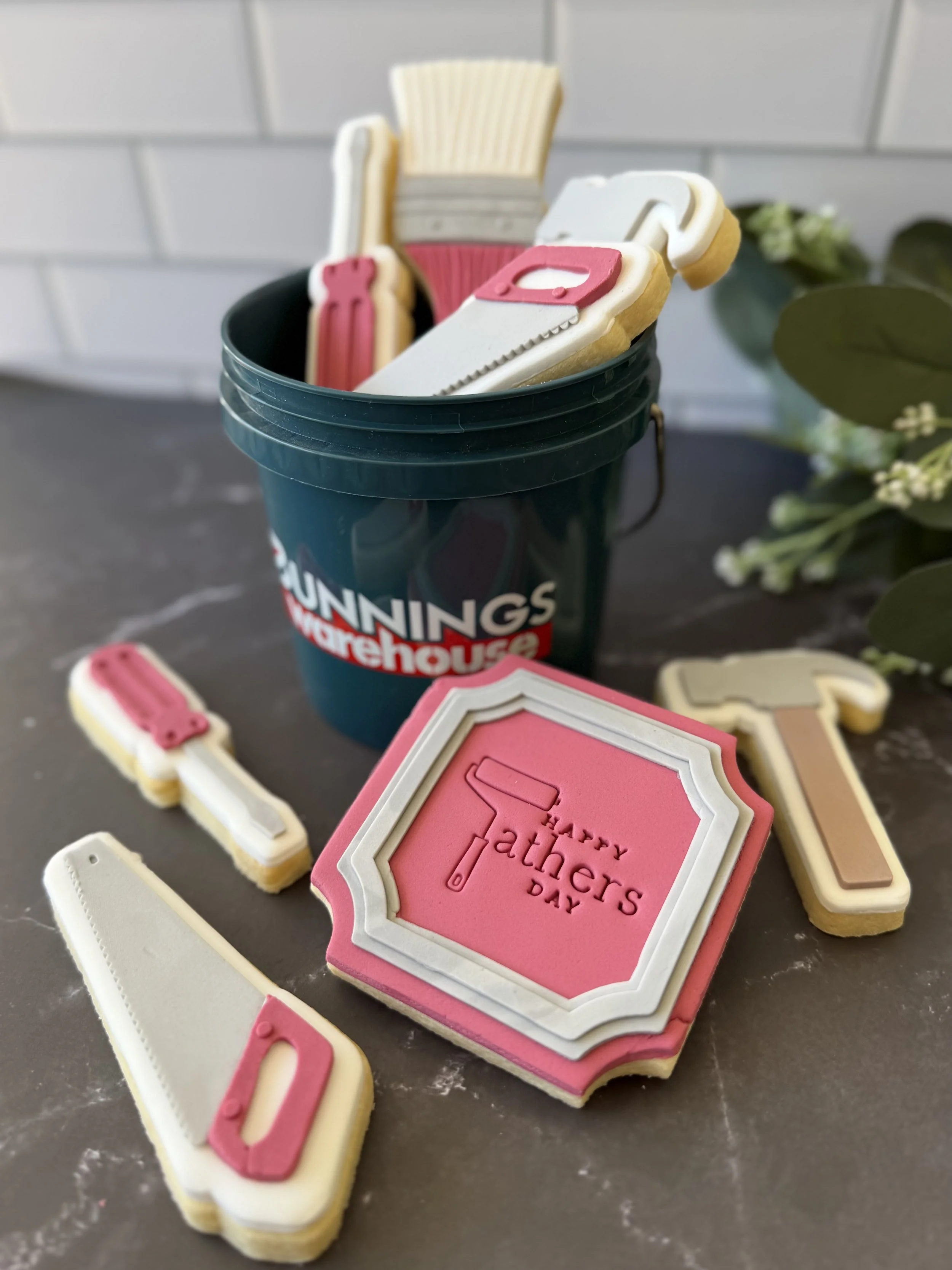 Custom father's day tool-theme cookies featuring saws, paintbrushes, hammers and a personalised plaque