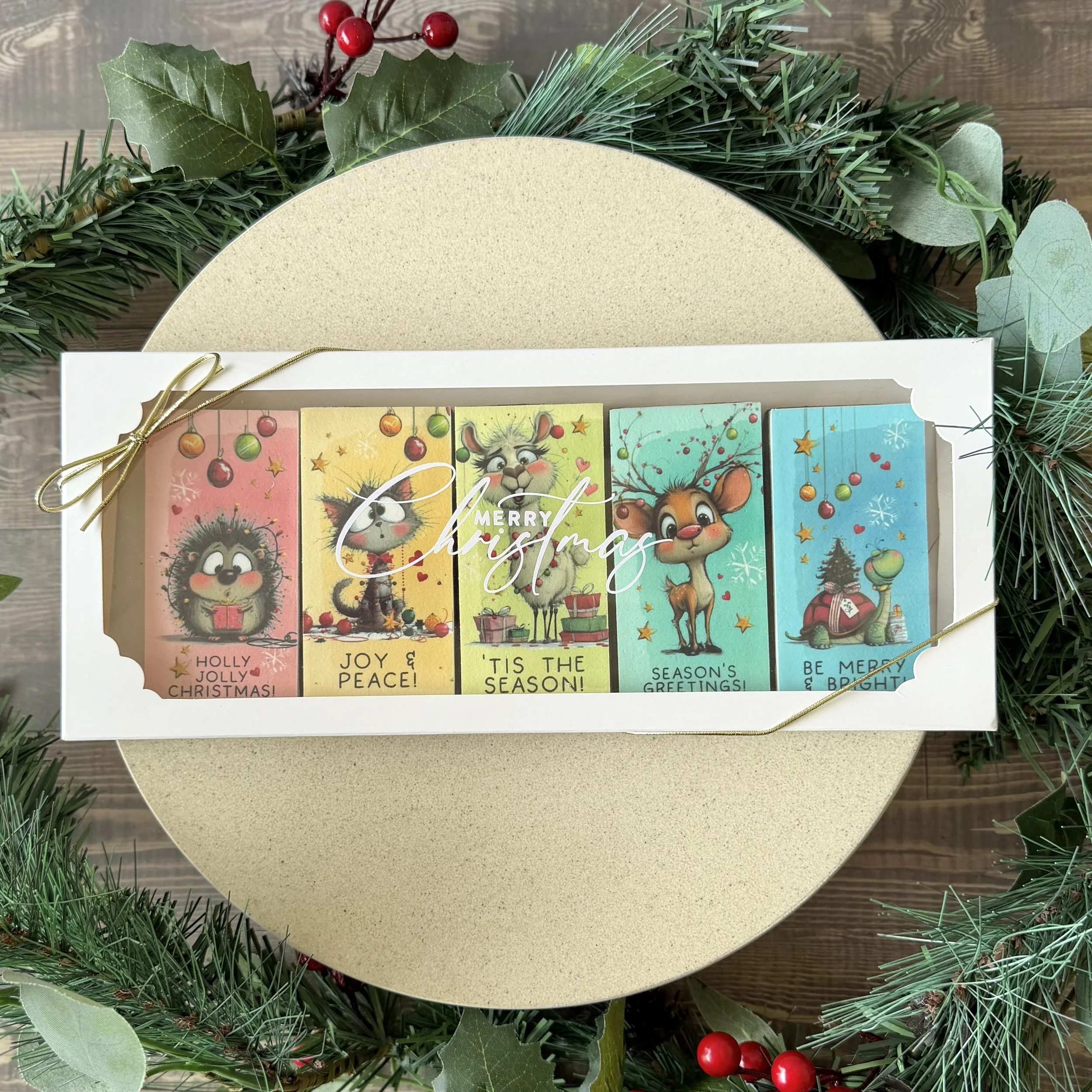 Holiday greeting cookie pack with festive illustrations of reindeer and holly, surrounded by Christmas greenery and red berries
