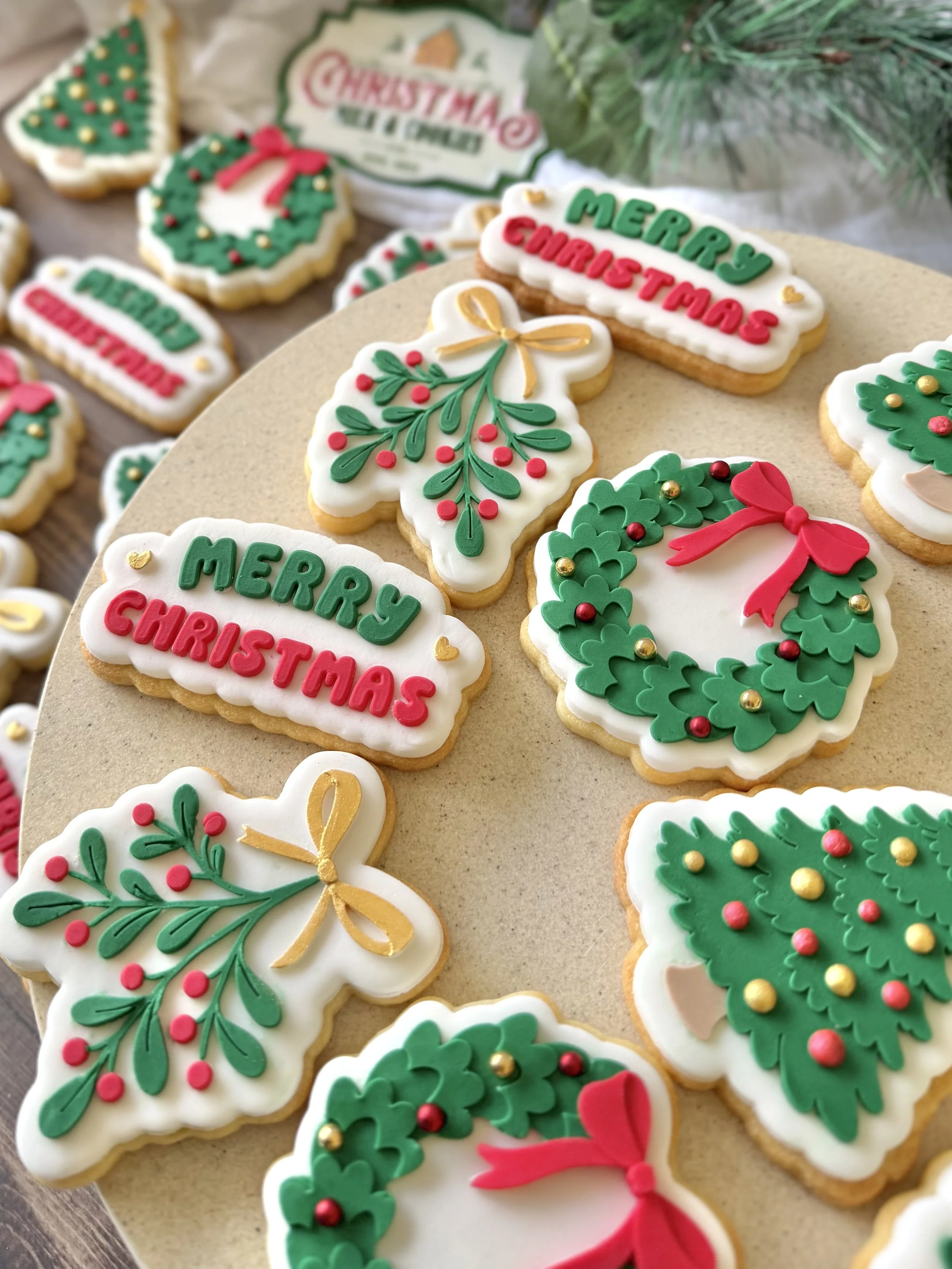 Decorated Christmas cookies with holiday themes, including wreaths, mistletoe, holly leaves, and messages such as "Merry Christmas."