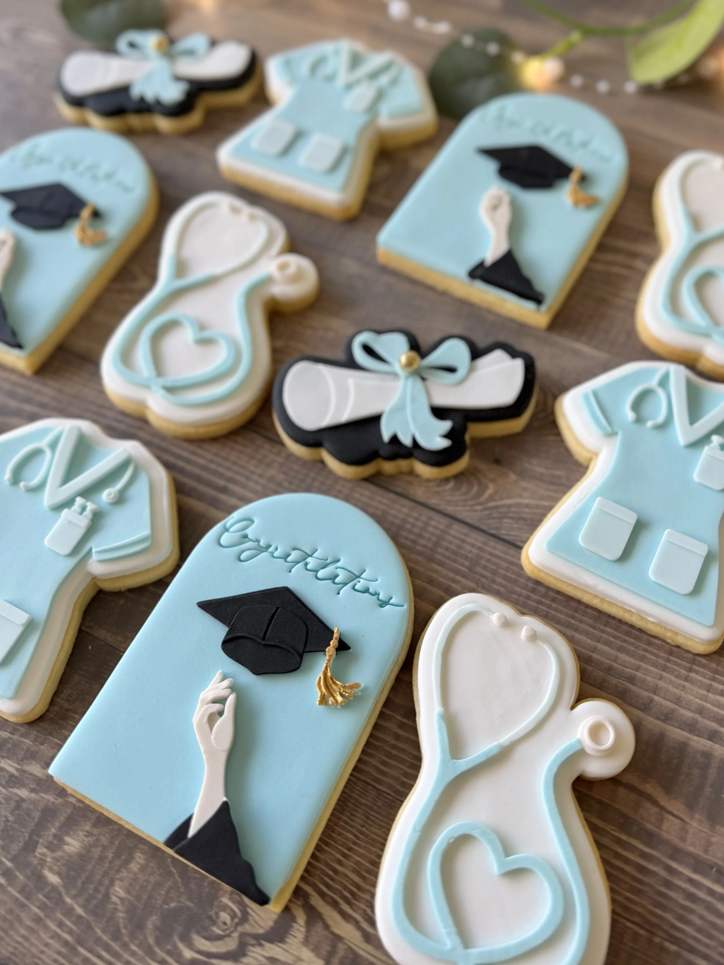 Decorative cookies with graduation-themed designs, including diplomas, graduation caps, and the word 'congratulations'