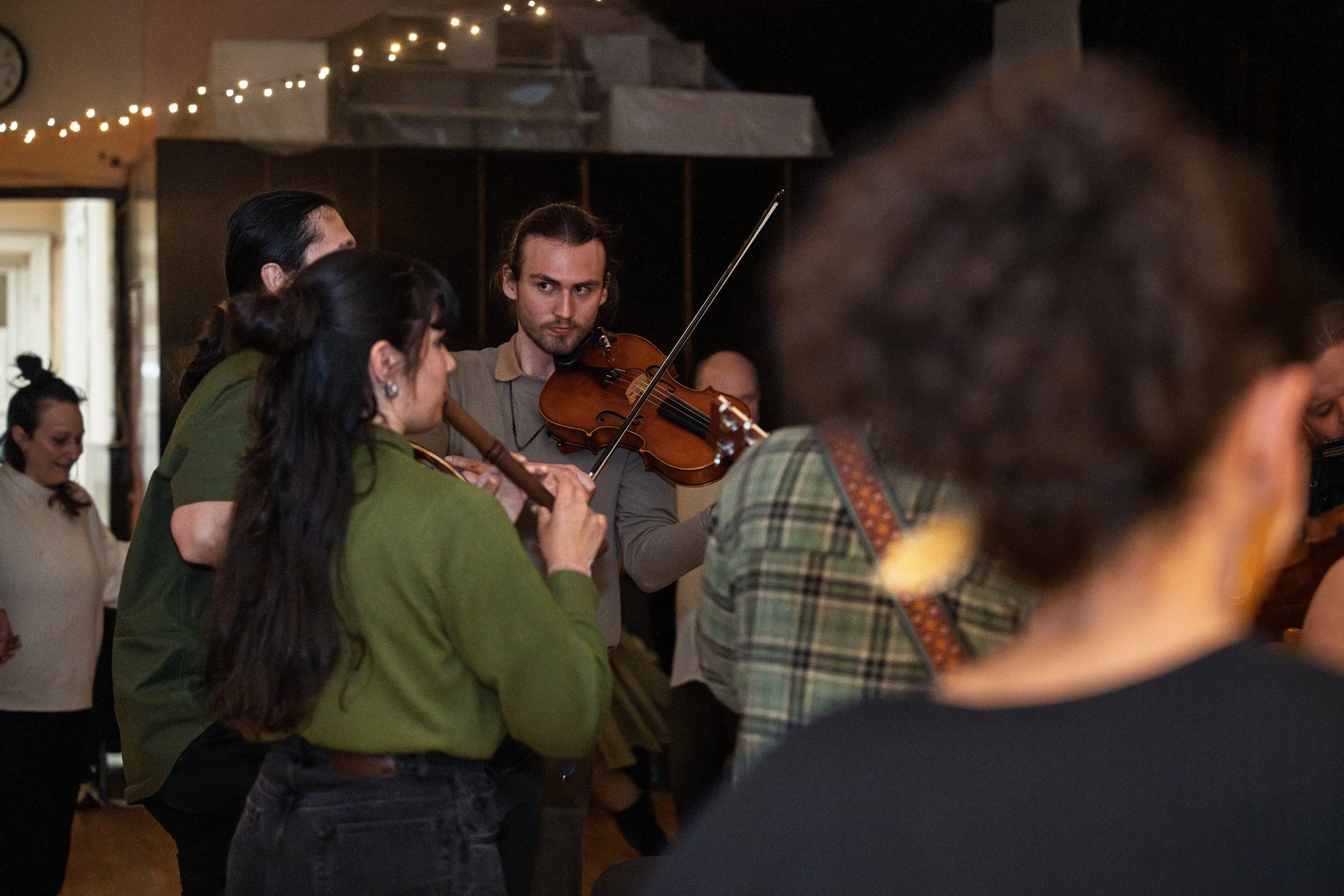 Group of people making music together, including a young man playing a violin.