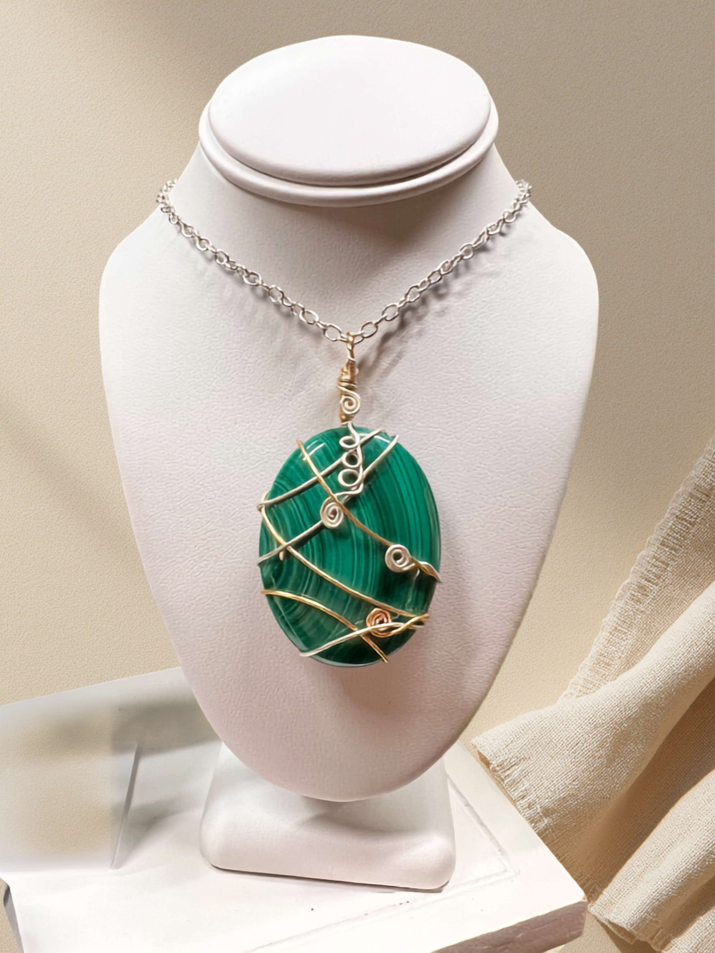 a beautiful wire wrapped malechite pendant dislpayed on a small display bust