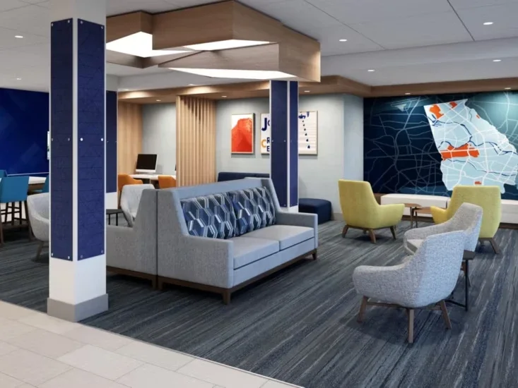 Modern airport lounge with various seating areas, a large map on the wall, and a desk with a computer in the background.