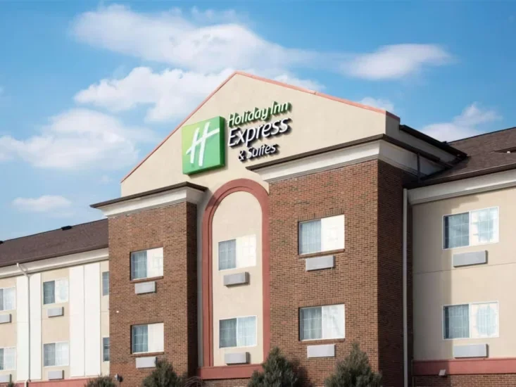 Exterior view of a Holiday Inn Express & Suites hotel with a brick facade and the hotel sign at the top.