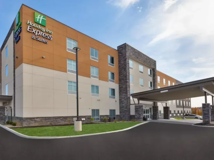 Exterior view of a Holiday Inn Express & Suites hotel building with a parking area and entrance canopy.