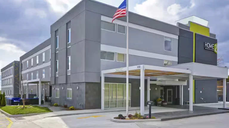 Exterior view of a modern multi-story hotel with a flagpole, American flag, and a covered entrance.