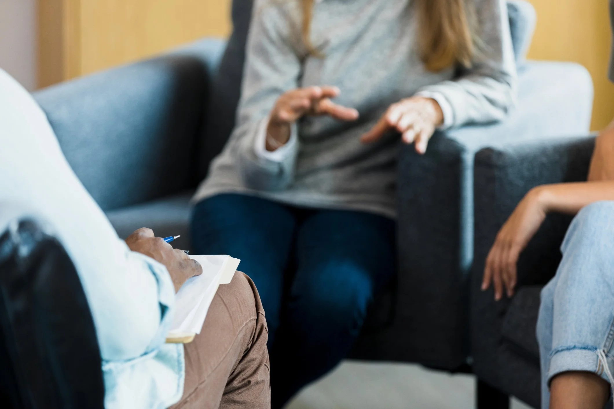 Group of people sitting in a circle, engaging in a discussion in a casual setting.