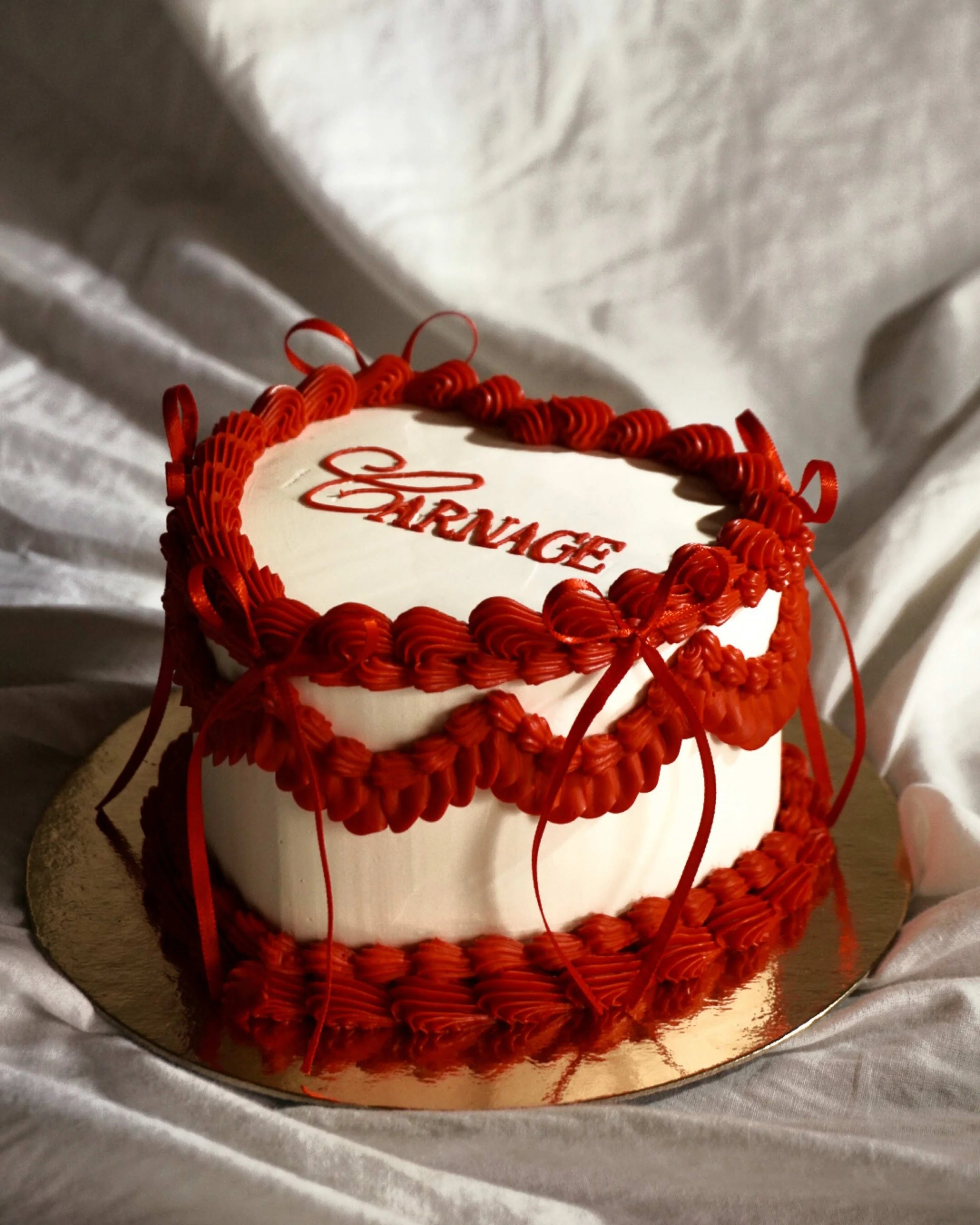 Un gâteau de forme sphérique avec une décoration en fil rouge, surmonté d'une inscription en rouge 'SIGNORE'.