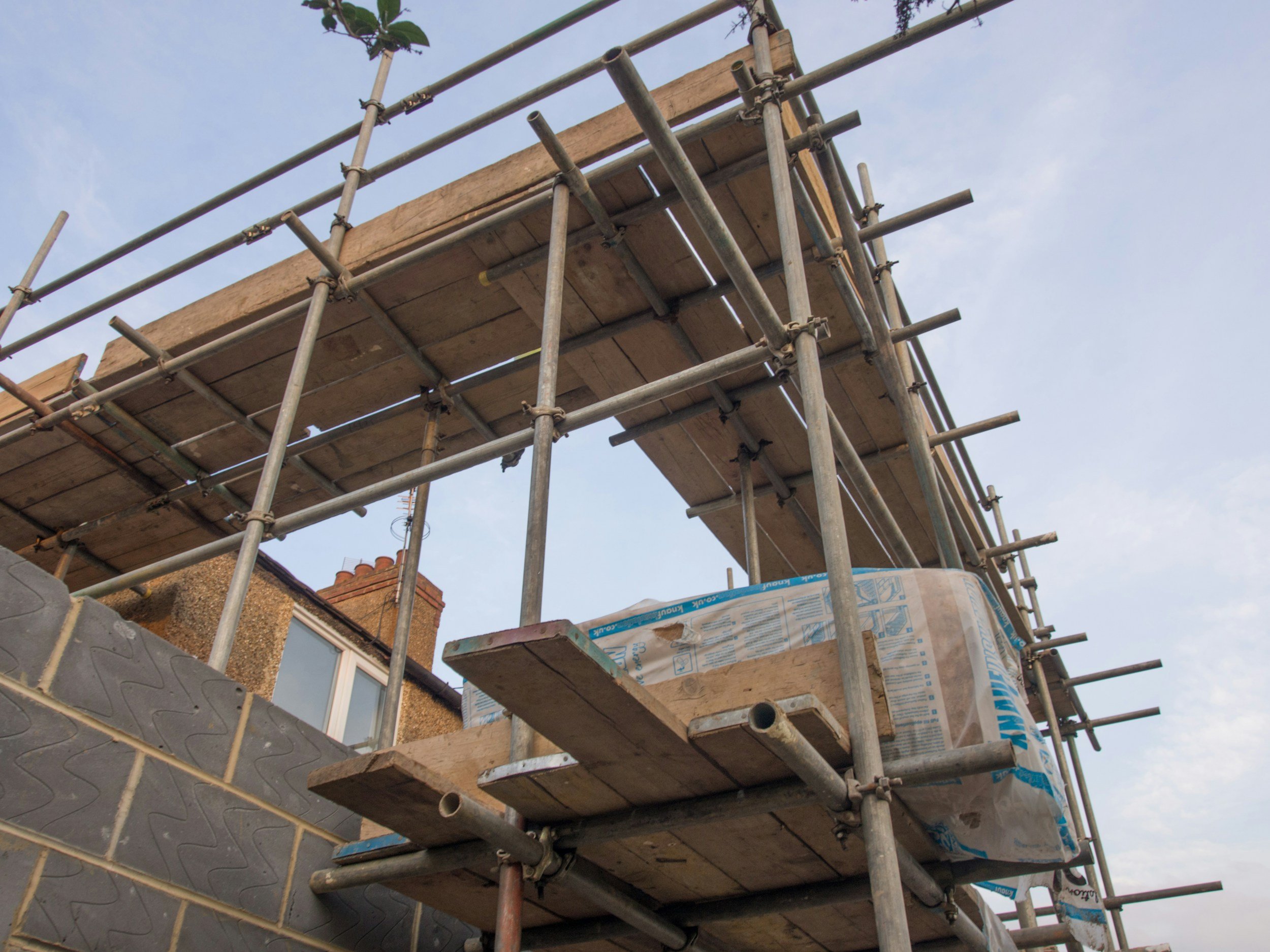 Scaffolding on the exterior of a building under construction with a blue sky in the background.