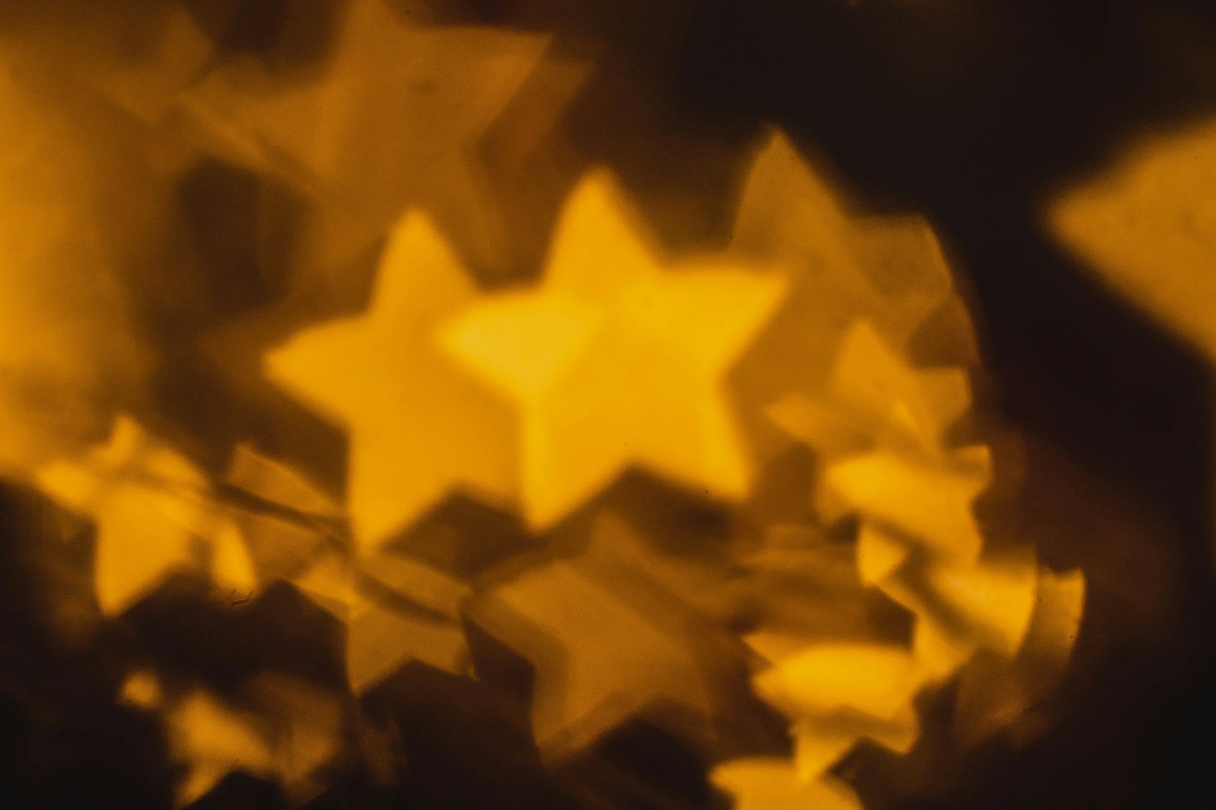 Close-up of star-shaped paper lanterns glowing in warm yellow-orange light.