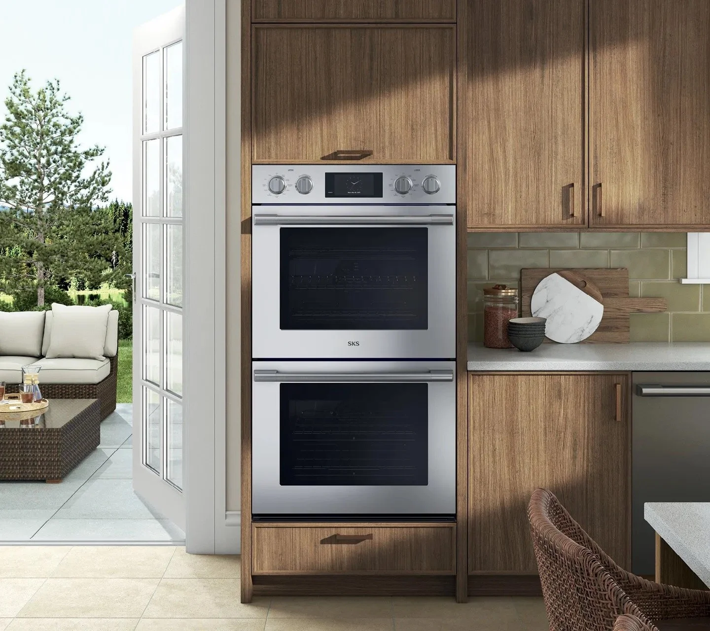 Kitchen with a double oven built into wooden cabinetry, countertops with various cutting boards and jars, and sliding glass door leading to outdoor patio with seating and greenery.