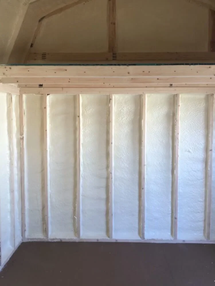 Interior wall with exposed wooden studs and spray foam insulation, part of a construction or renovation project.