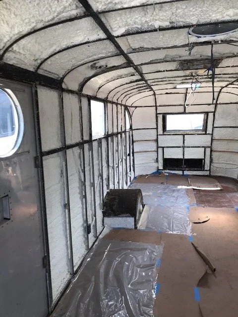The owners gutted an older RV down to the shell and are rebuilding the inside. There are no flat bays in here and nothing square to work against, so the foam has to follow the curve of every rib and hold there while it sets. Closed cell is the best w