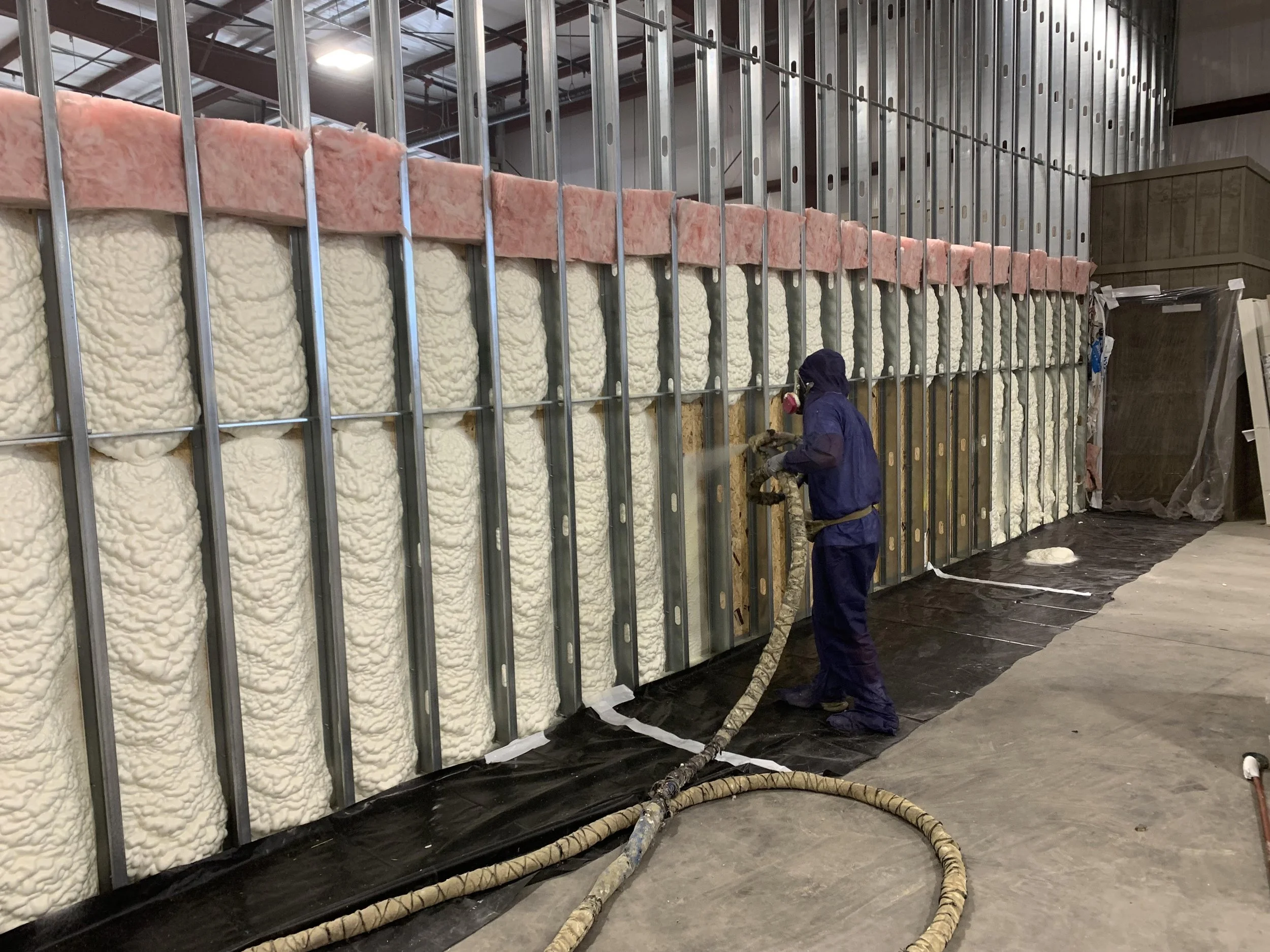 Worker inspecting metal framing and insulation in construction site.
