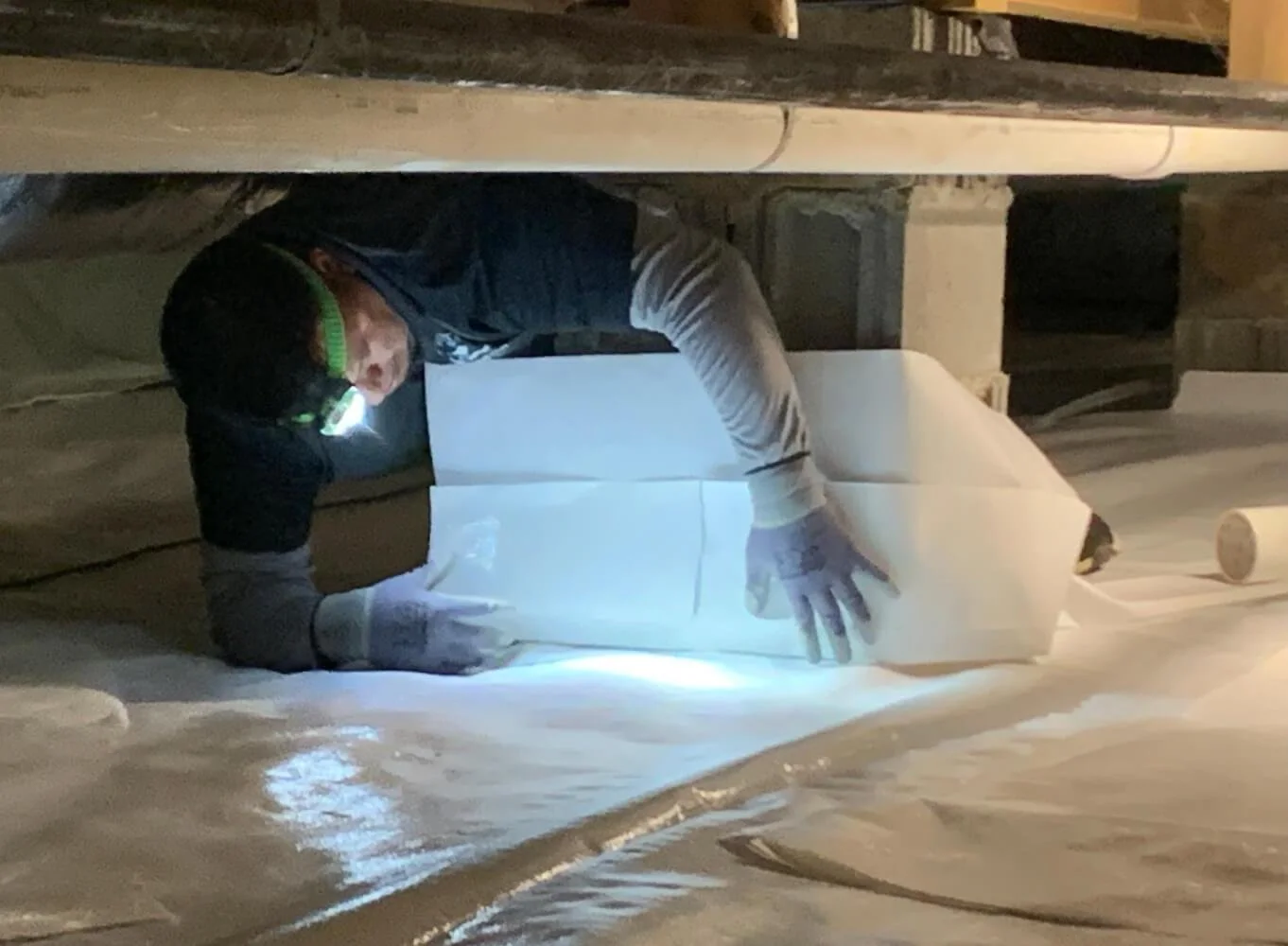 A person examining large white blocks in a dimly lit workshop or storage space, wearing gloves and using a flashlight.