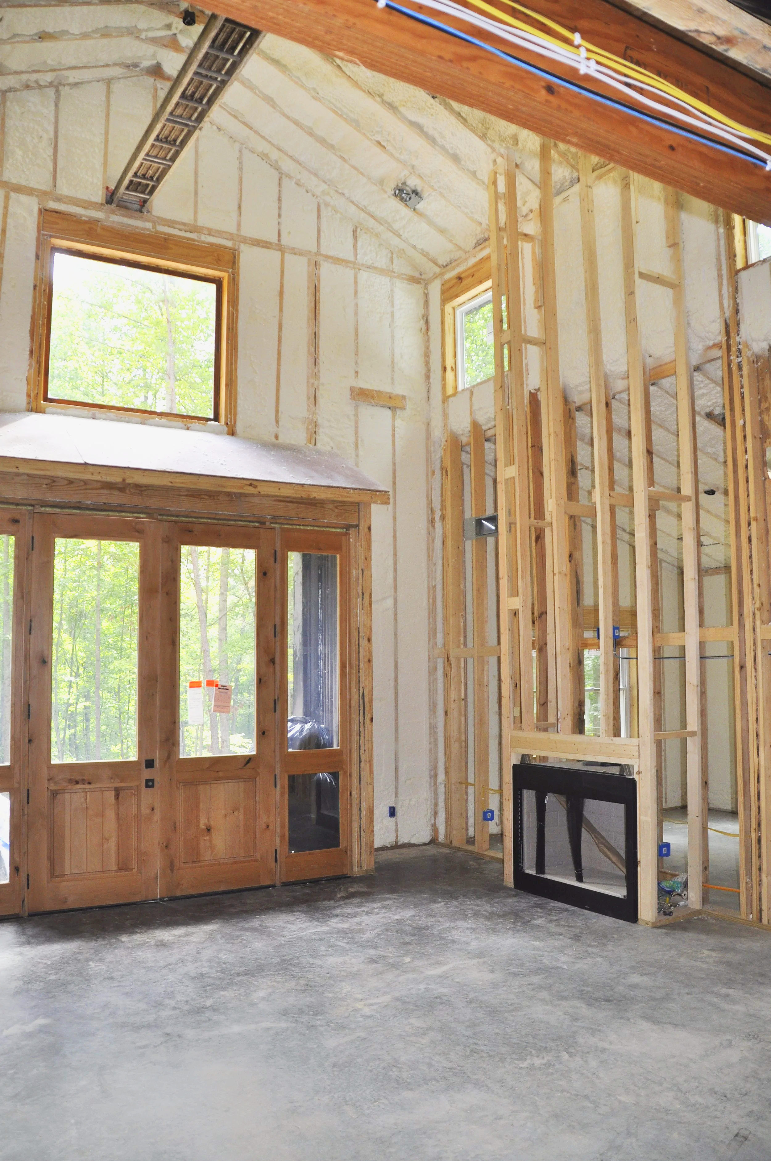 Interior of a house under construction showing unfinished walls, wooden framing, and installation of windows and doors.