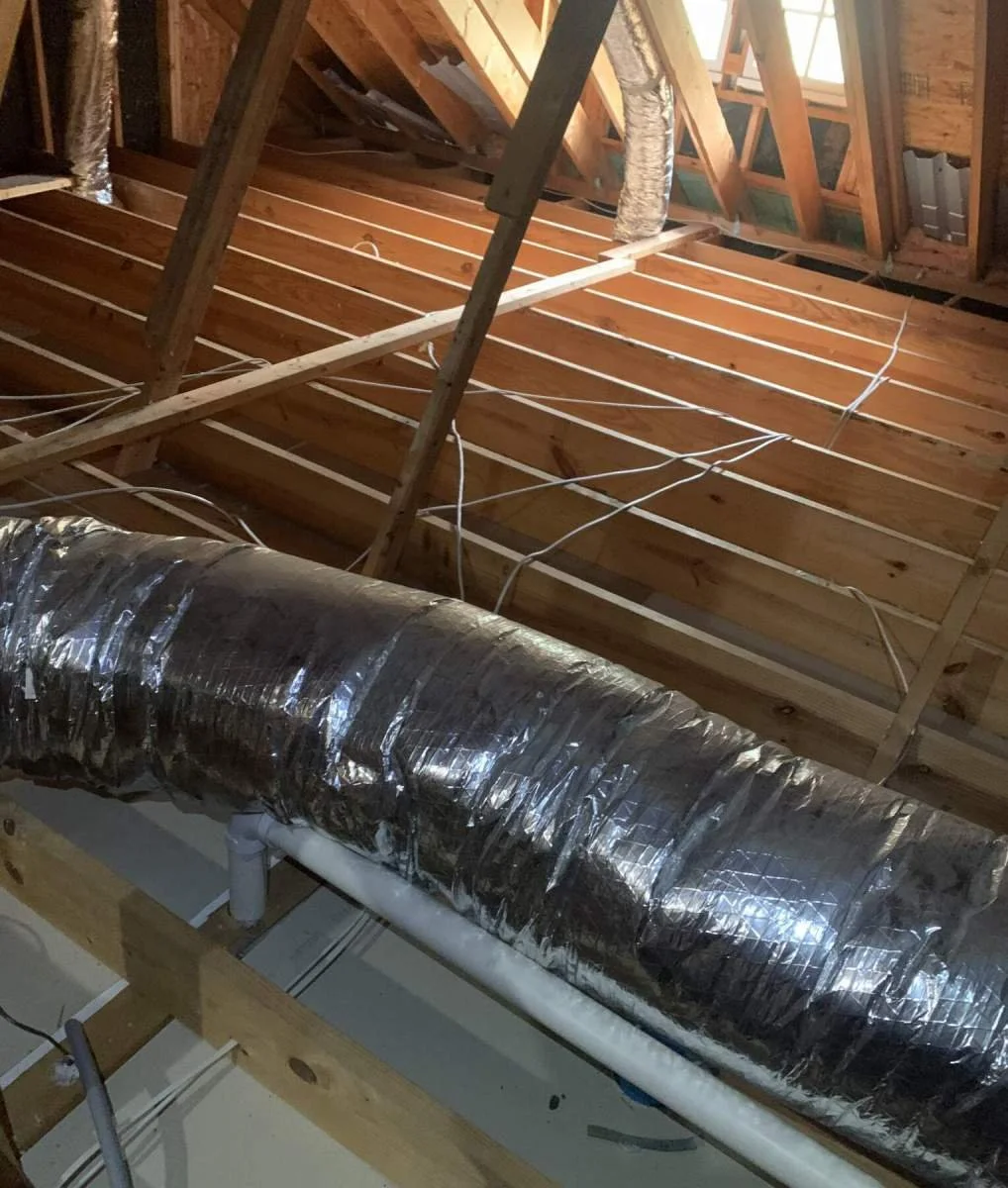Construction of a building's ceiling showing wooden framing, electrical wiring, and ductwork.