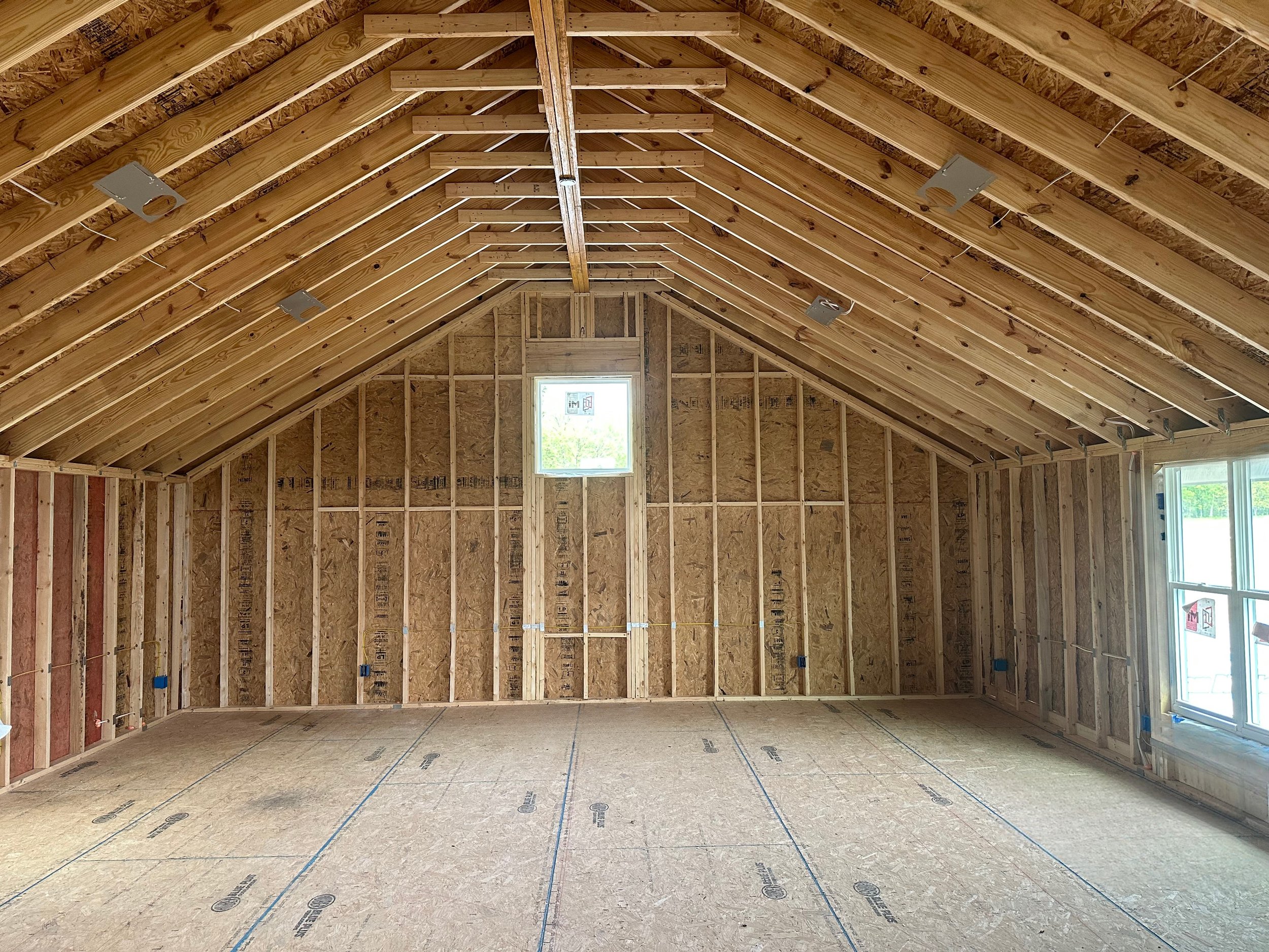 Unfinished interior of a building framed with wooden studs and beams waiting for spray foam insulation.