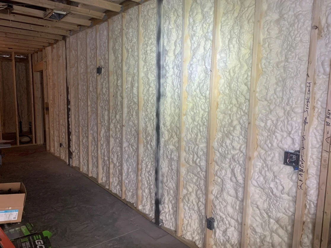 Interior wall in construction with spray foam insulation between wooden studs.
