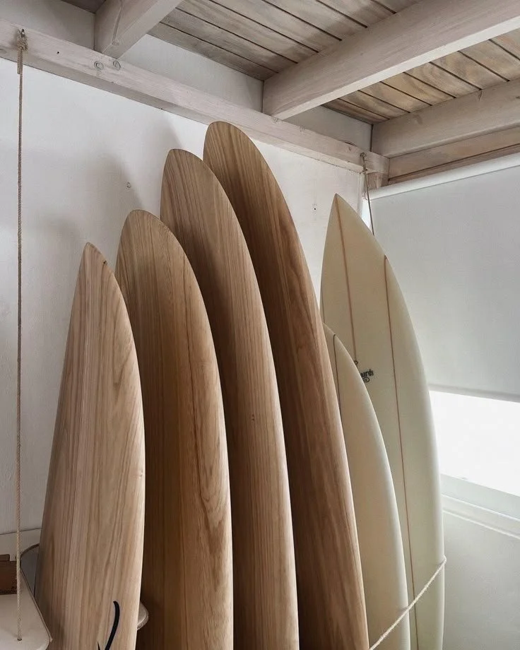 Several surfboards are standing upright against a wall inside a room with wooden ceiling beams.