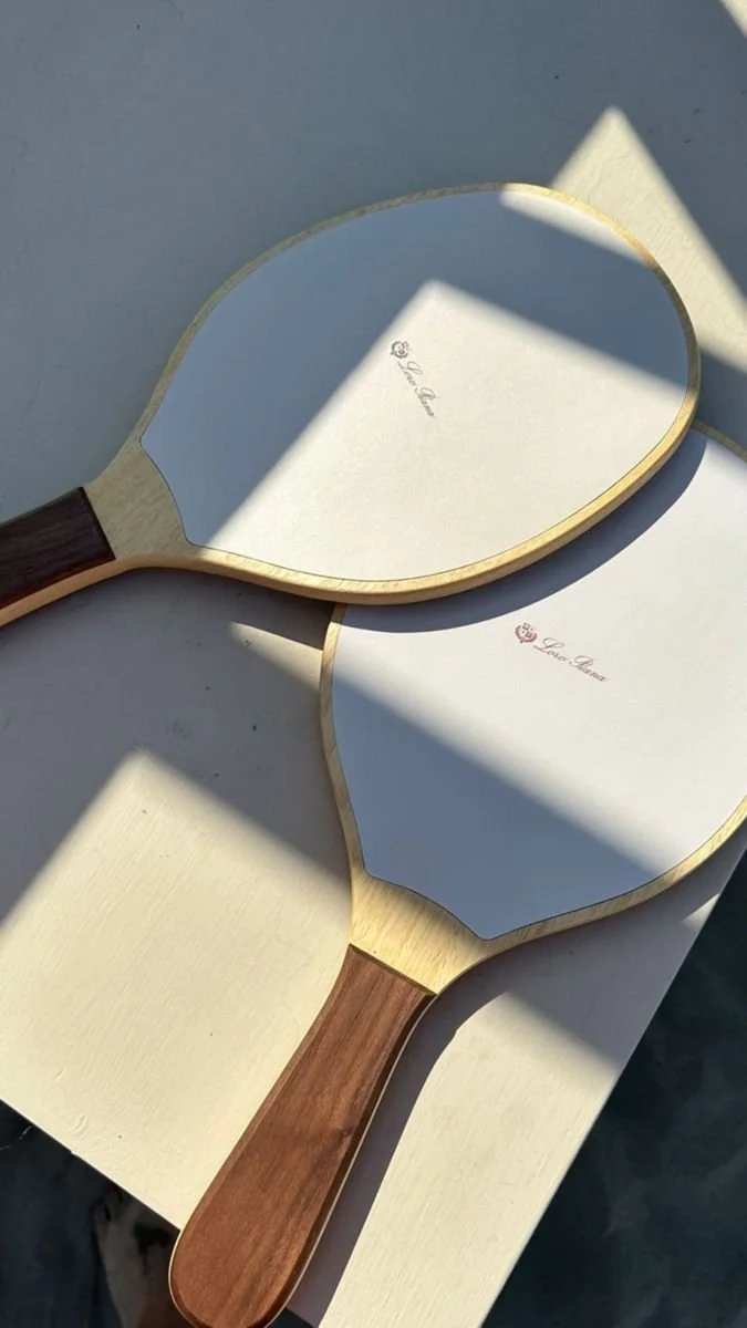 Two wooden handheld mirrors placed on a white surface, illuminated by natural sunlight.