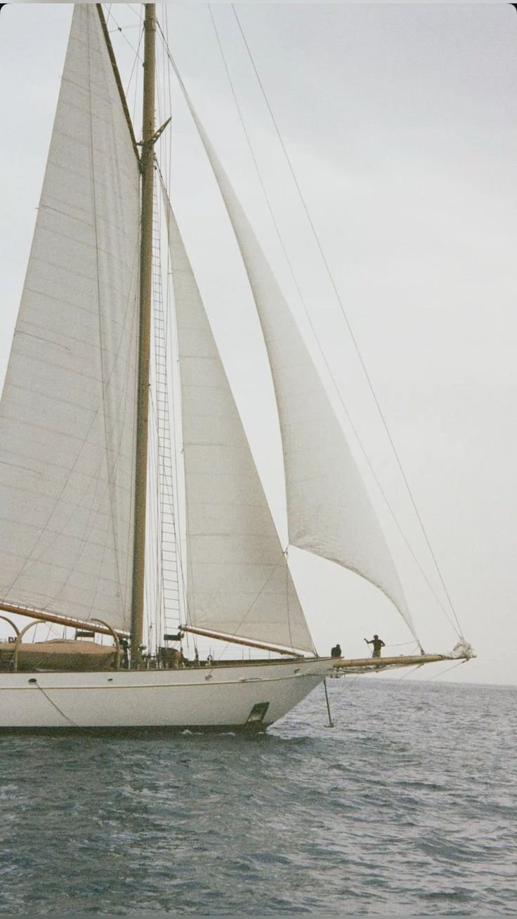 A sailboat with tall masts and large white sails on the open water.
