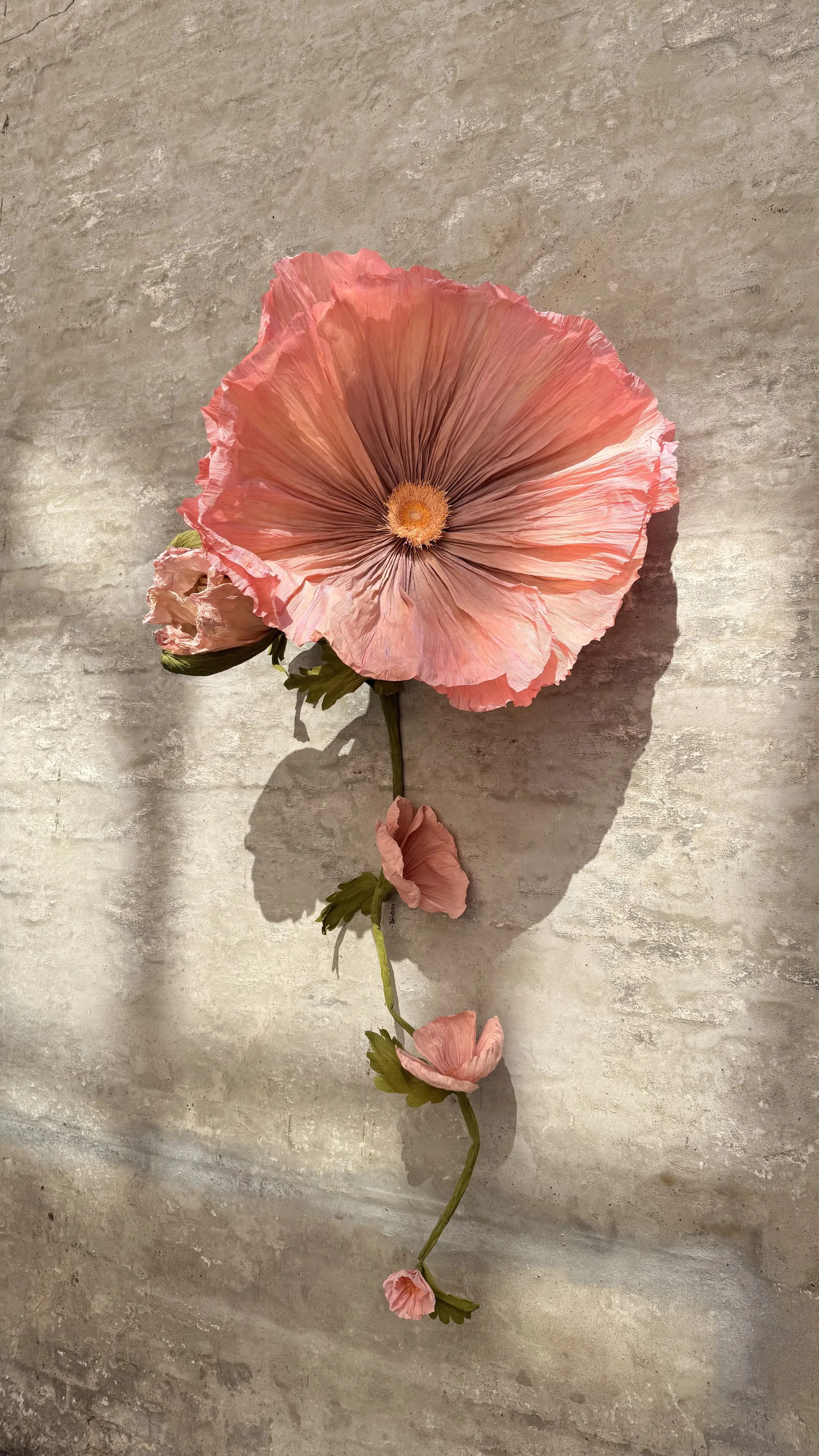Giant handcrafted paper poppy sculpture with sculptural stem and seed pods.