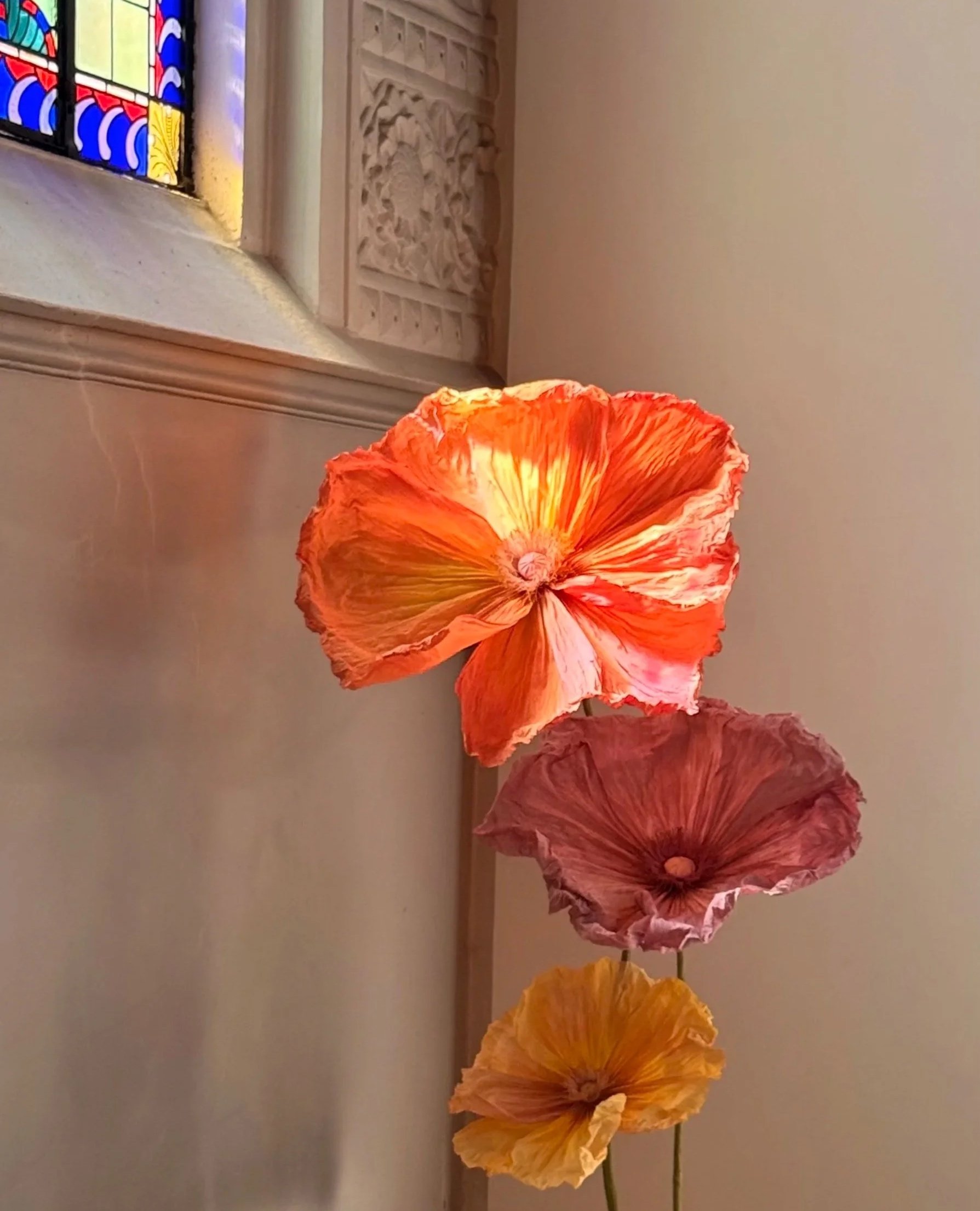 Collection of handcrafted giant paper flowers in vibrant shades of orange, yellow and pink.
