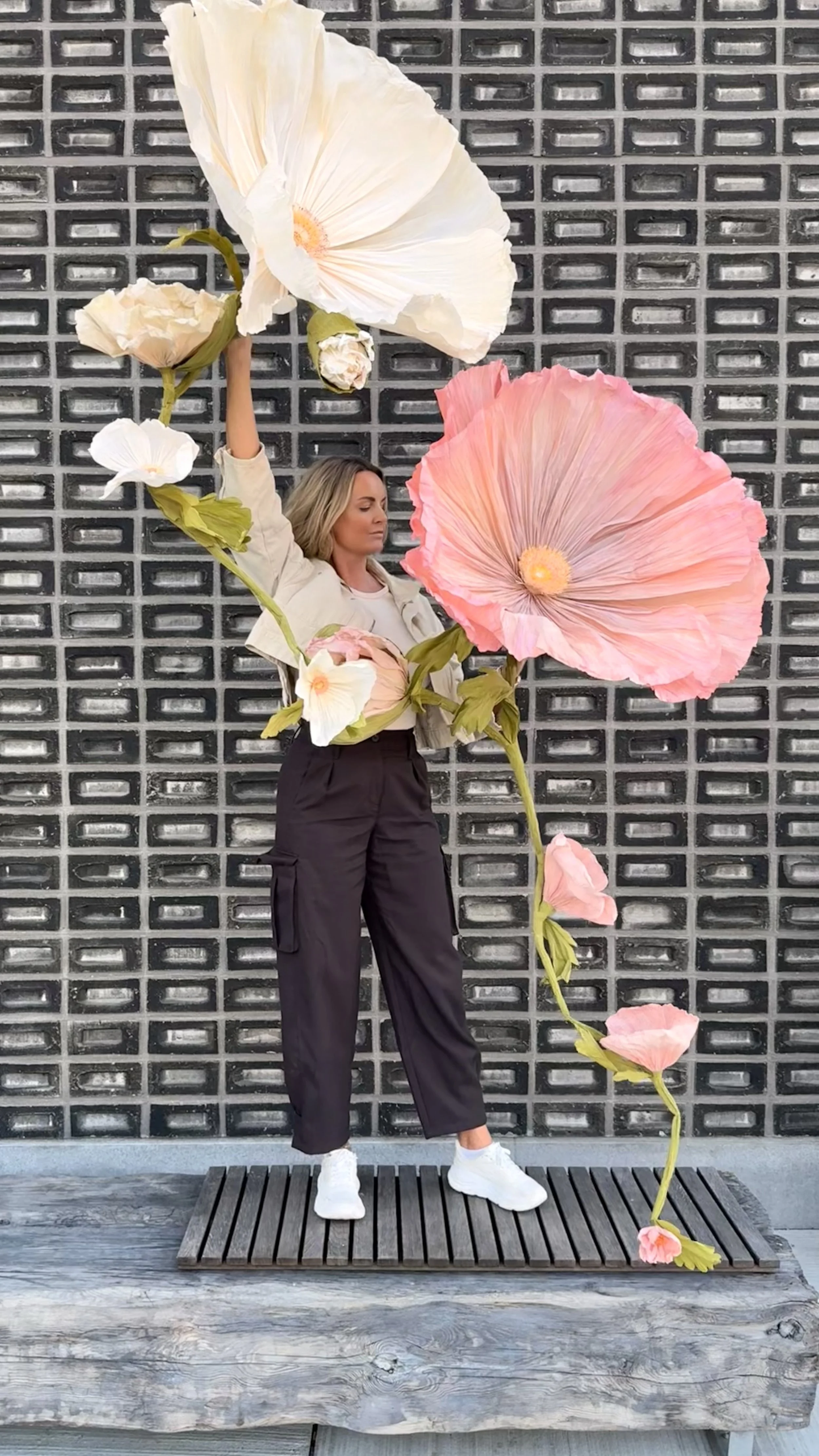 Artist Julia Midtgaard holding whimsical giant handcrafted paper poppies