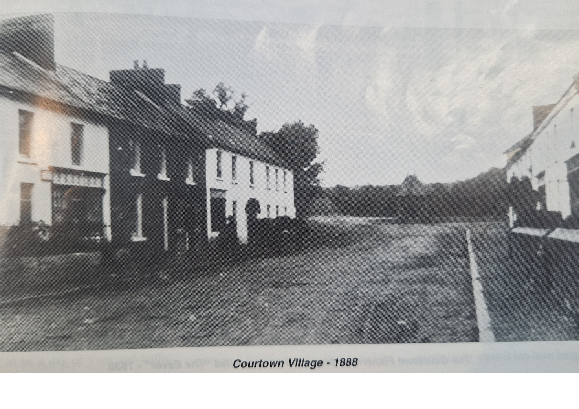 Black and white photograph of Courtown Village in 1888 showing several buildings, a dirt street, and trees in the background.