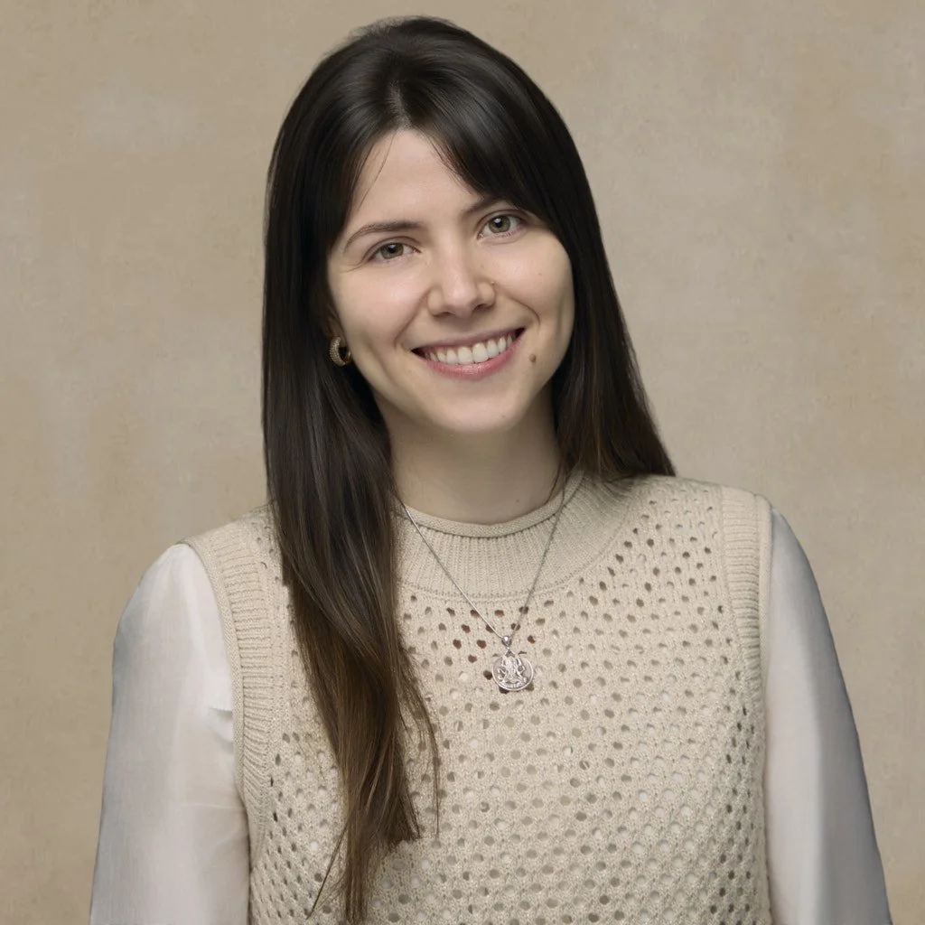 A young woman with long brown hair, wearing a beige sleeveless knit vest over a white long-sleeve shirt, smiling in front of a plain beige background.