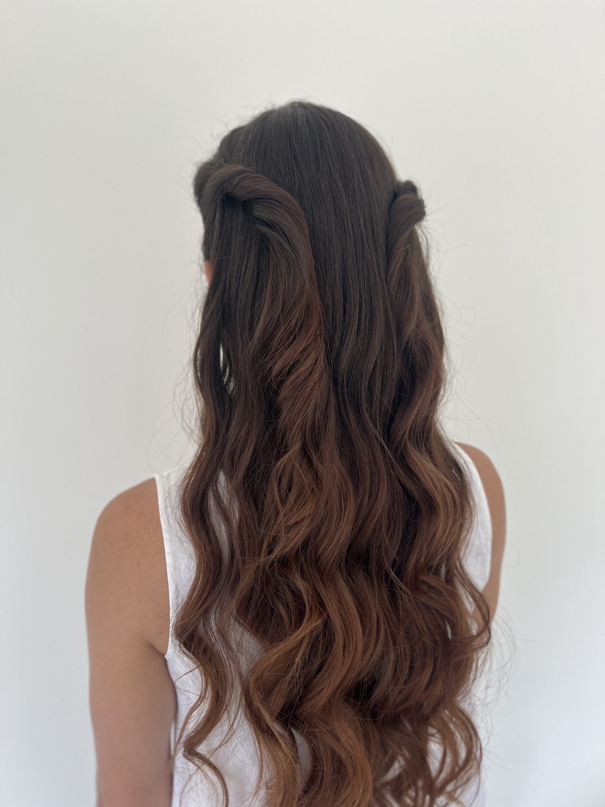 Chaîne de cheveux bouclés colorés marron et auburn portée par une personne photo prise de dos contre un fond blanc.