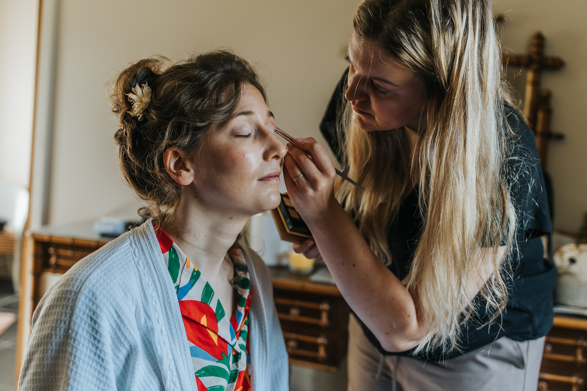 Une femme appliquant du maquillage sur une autre femme lors d'une séance de maquillage ou de préparation.