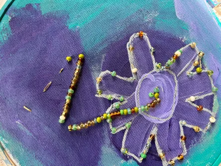 A beaded bracelet and a string of beads arranged on a purple fabric background, with a heart shape drawn in chalk.
