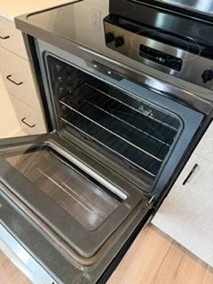 Open kitchen oven with visible racks inside and a stovetop on top.