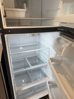 Empty refrigerator with open door, shelves and compartments visible.