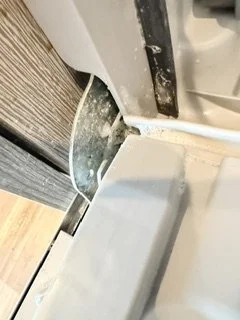 Close-up of a window frame with a partially open sliding window and a white frame, showing some dust and dirt around the edges.