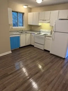Kitchen with white cabinets, a white oven, and a white refrigerator, yellow backsplash, wood flooring, and a window.