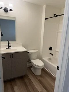 Bathroom with a sink, mirror, toilet, and bathtub with a shower curtain rod.