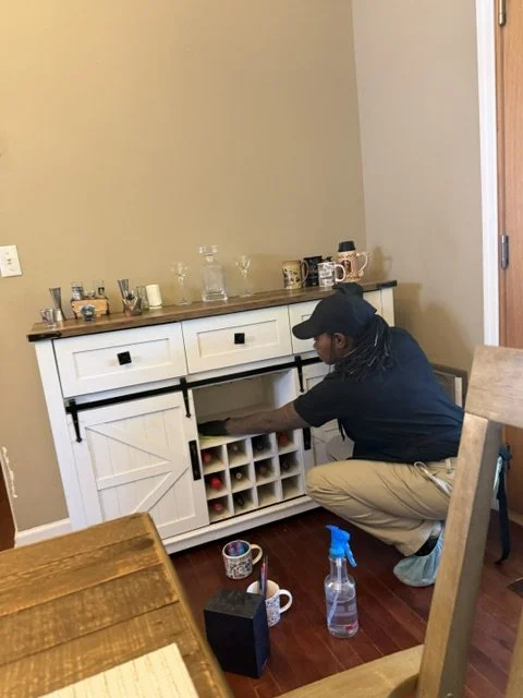 Person organizing wine bottles inside a white cabinet in a kitchen area.