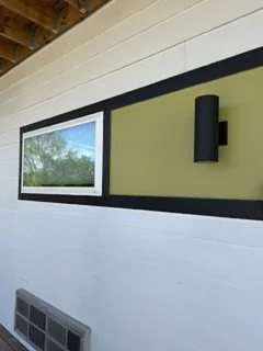 Interior wall with a horizontal window, black wall-mounted light fixture, and vent below the window.