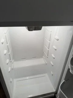 Empty white refrigerator interior with shelves and door compartments.