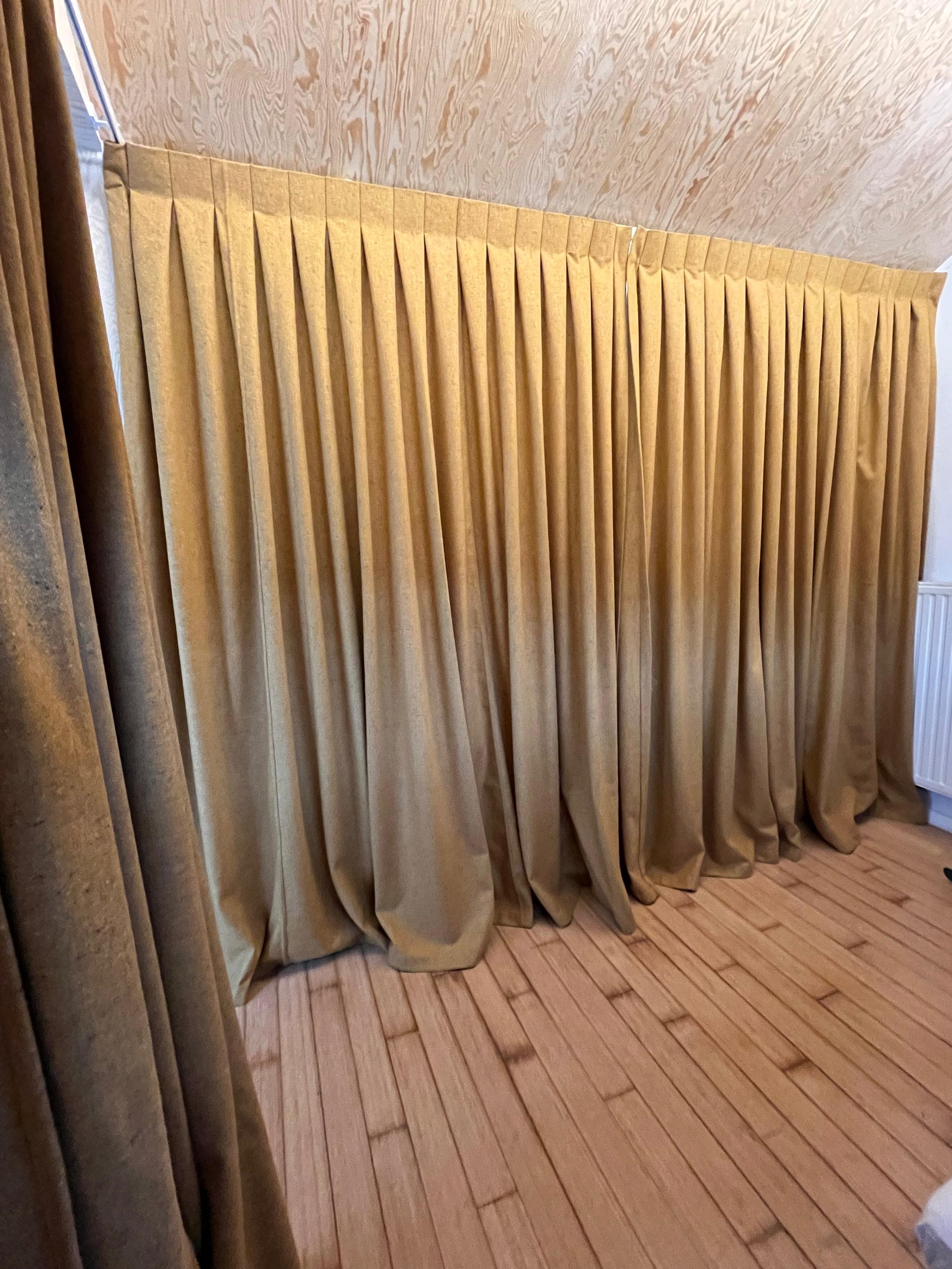 Rideau beige en tissu plié dans une pièce avec un sol en bois