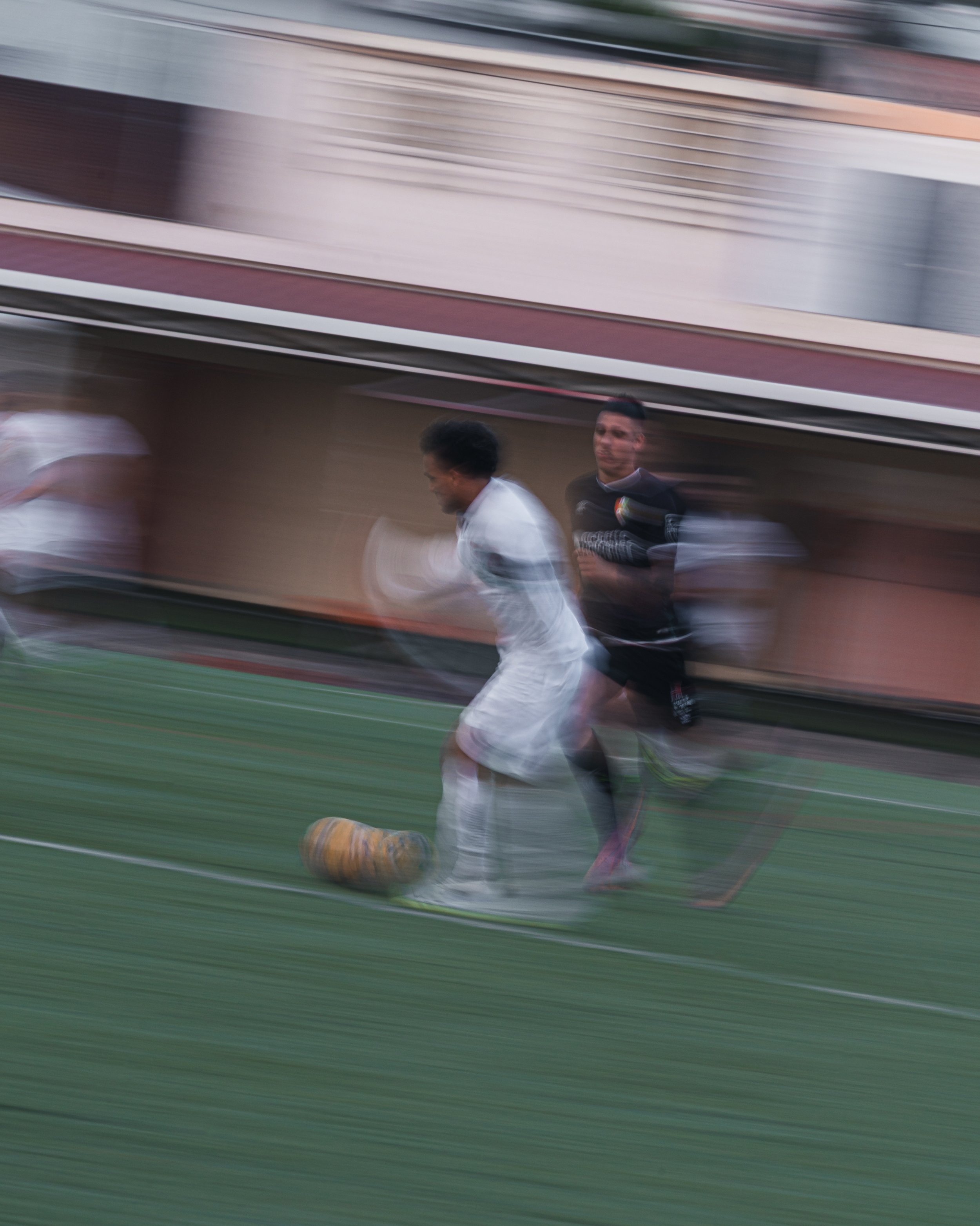 People playing football on a field, with motion blur indicating fast movement.