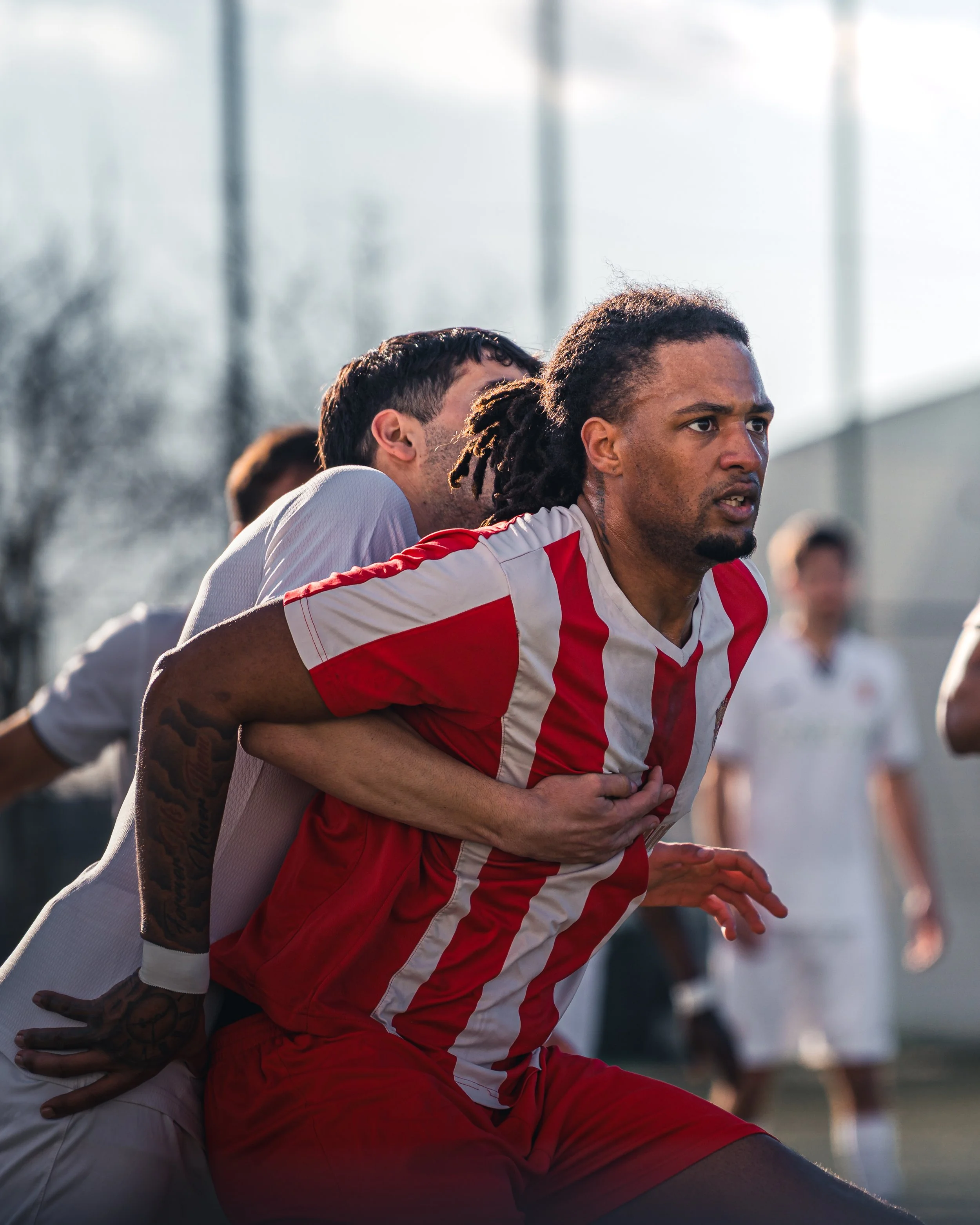 Football players in a tense game on a sunny day.