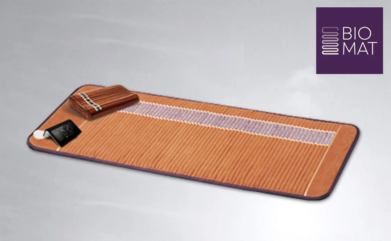 An orange mat with a striped pattern, a small pile of wooden sticks, and a black card on it, with a purple logo in the top right corner that reads 'BIO MAT'.