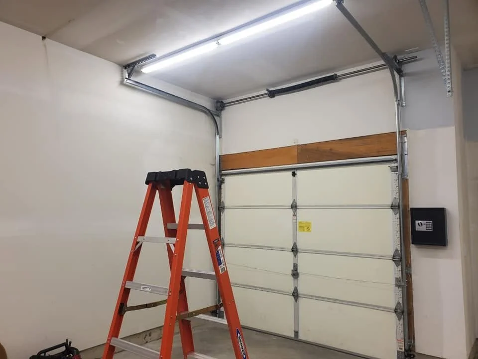 Empty garage with a red ladder, a garage door with a keypad, and an electronic opener with visible tracks.