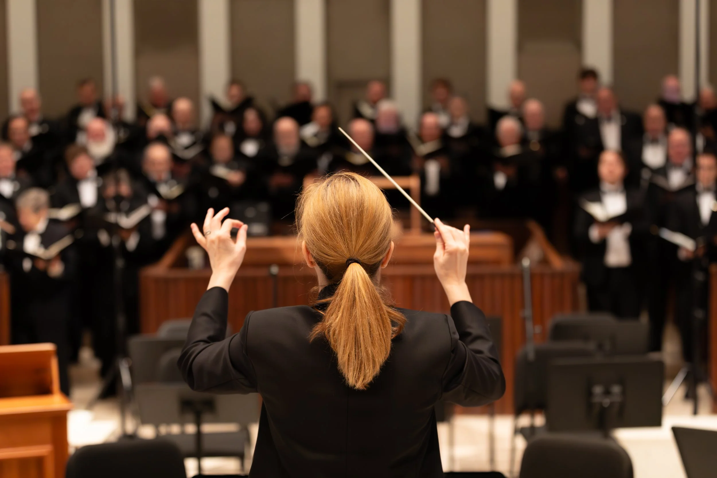 City Choir Artistic Director Erin Freeman conducting, seen from behind.